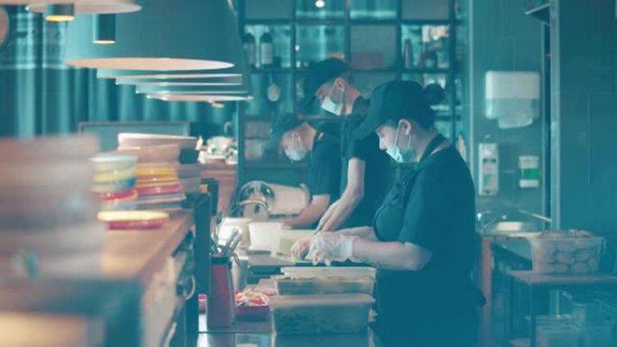 戴着口罩的餐厅人员在开放式厨房做饭