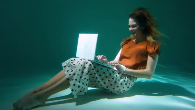 微笑美丽的年轻快乐忙碌的女商人，客户服务代表使用笔记本电脑水下慢动作。