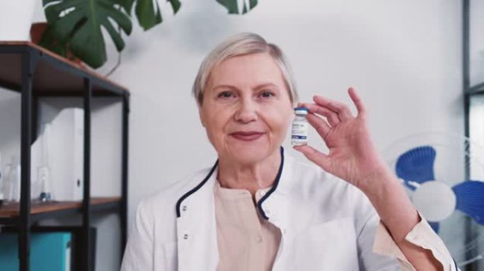 冠状病毒疫苗。自信的高级药房医生穿着实验室外套的女人对着镜头微笑，展示了新型冠状病毒肺炎的治疗方法。