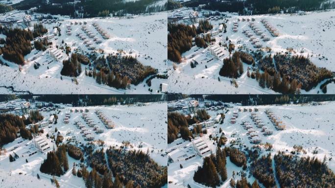 无人机在美丽的冬季度假胜地，早晨的木屋村，晴天白雪覆盖的山脉中放大。