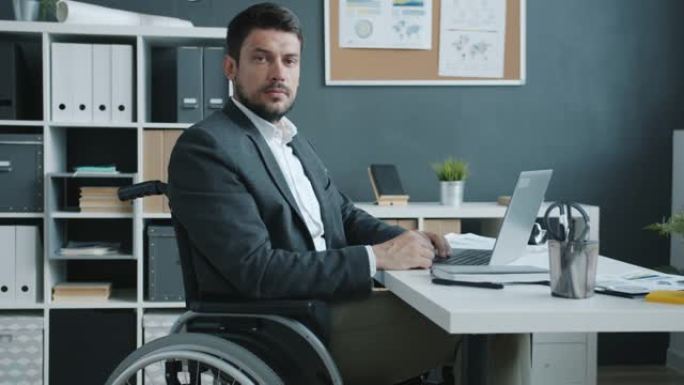 坐在轮椅上看着相机的残疾商人的慢动作肖像