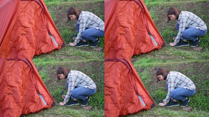 女旅行者在山上的露营地搭建帐篷
