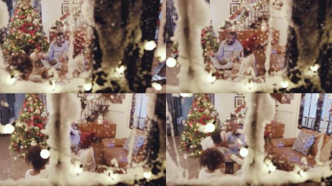 快乐的多民族家庭玩得开箱庆祝圣诞节假期，冬天和圣诞节场景概念从下雪的窗户看到雪落下