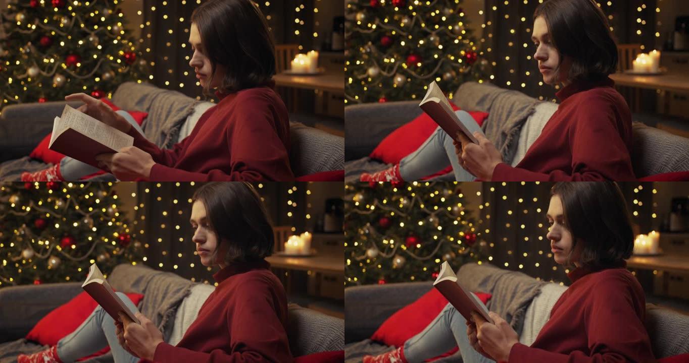 一个穿着舒适的红色毛衣的漂亮棕色头发的女人读了一本有趣的书，坐在美丽的圣诞节室内沙发上，
