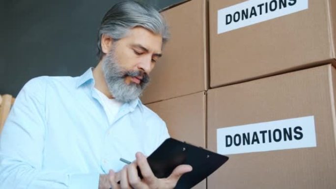 成熟男人慈善公司经理在储藏室用捐款箱做文书工作