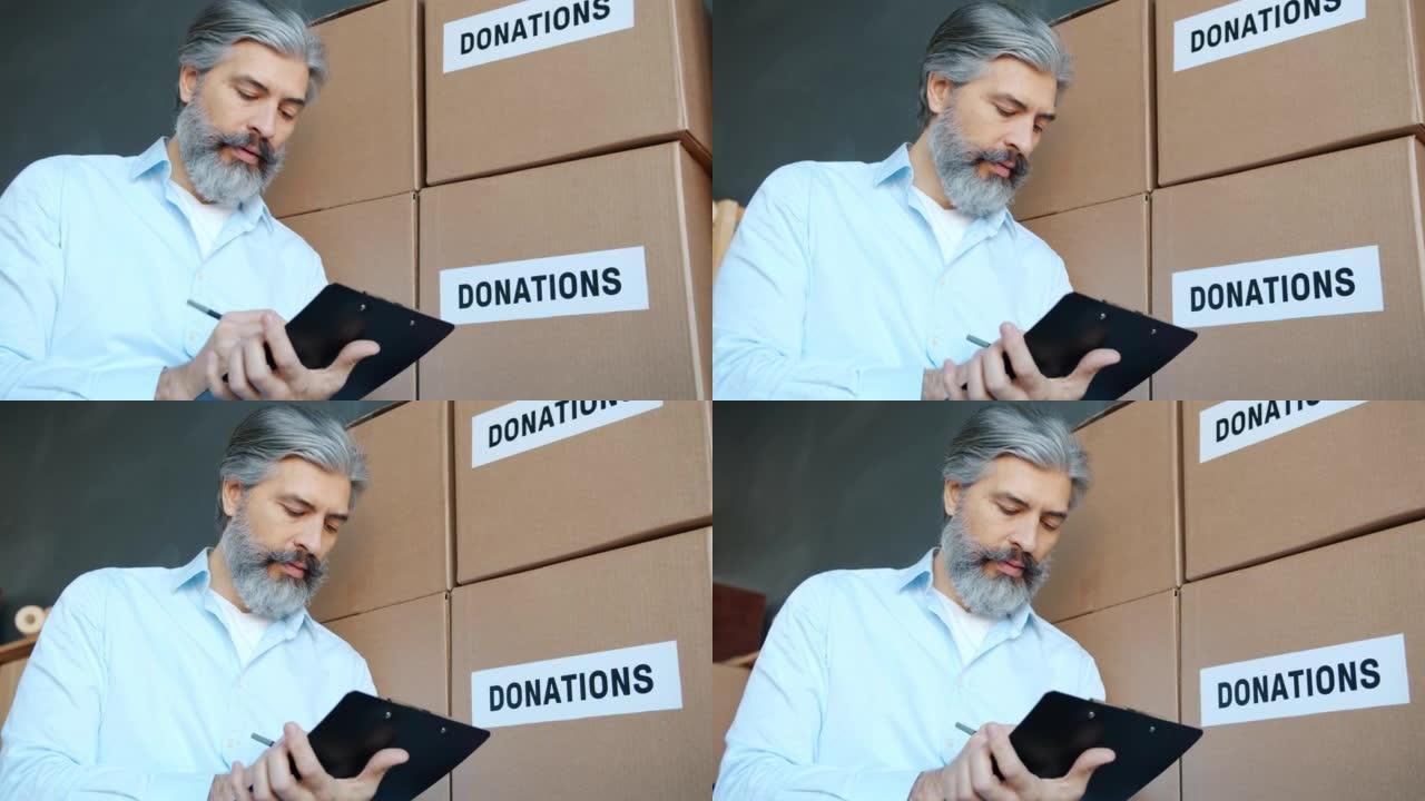 成熟男人慈善公司经理在储藏室用捐款箱做文书工作