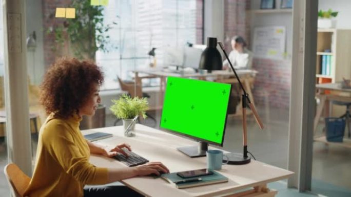 中东女性在创意机构工作，为客户实施现代商业战略。成功的专家使用带有绿屏模拟显示的计算机。以上角度拍摄