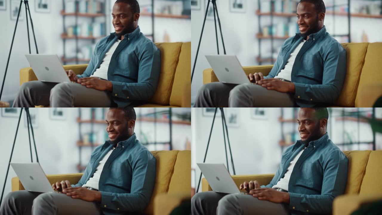 英俊的黑人非洲裔美国男子坐在舒适的客厅的沙发上，在笔记本电脑上工作。自由职业者在家工作。浏览互联网，