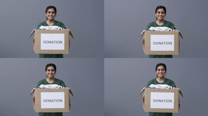 4k视频片段，一名妇女拿着一盒衣服，上面写着 “捐赠” 字样