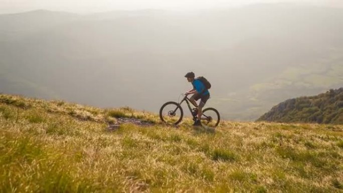 男性运动员山地自行车在山区的草地上骑自行车