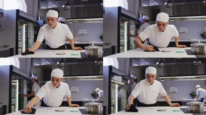 一位专业的高加索男厨师穿着清洁台面，同事正在工作