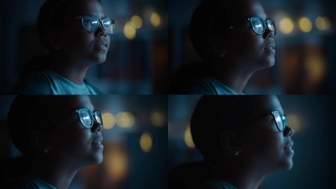 一个十几岁的多民族黑人女孩兴奋地看着窗外的肖像。惊讶的年轻女性在家里看着夜空。她戴着眼镜和牙套。