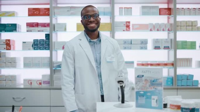 药房药店收银台: 英俊的职业黑人男药剂师穿着白色实验室外套，看着相机，微笑的肖像。货架上有药品包装、
