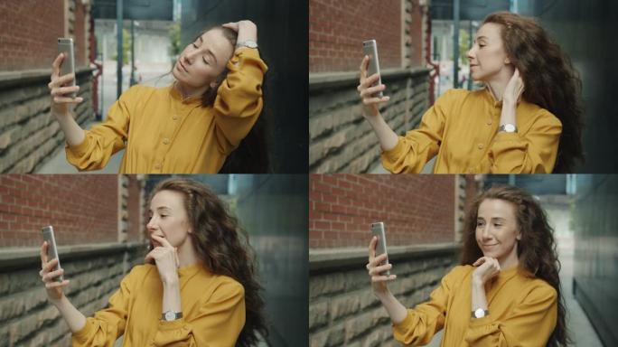 美丽的年轻女士在街上使用智能手机相机自拍的慢动作