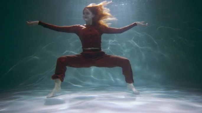 年轻美丽有趣快乐活跃的红发女人在水下慢动作下做有趣的蟹舞动作的电影镜头。