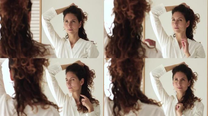 沉思的女人照镜子触摸她的卷发