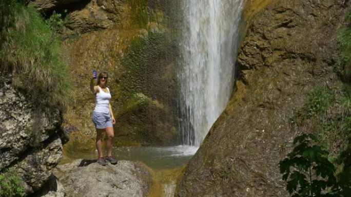 复制空间: 年轻女子在斯洛文尼亚美丽的瀑布旁自拍。