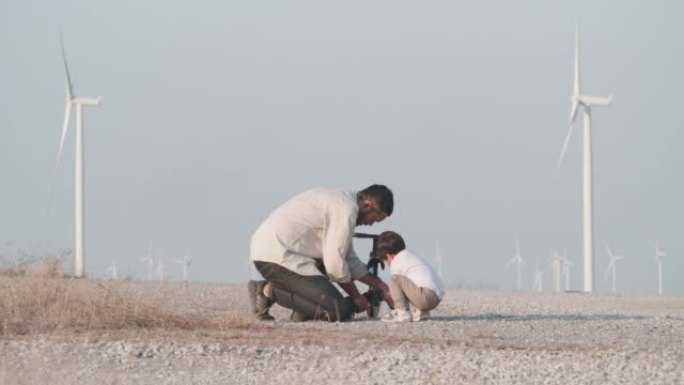 幸福的家庭父亲教2岁的孩子儿子第一次上课，在风力涡轮机之间骑自行车，自由自在。教孩子们关于可持续发展