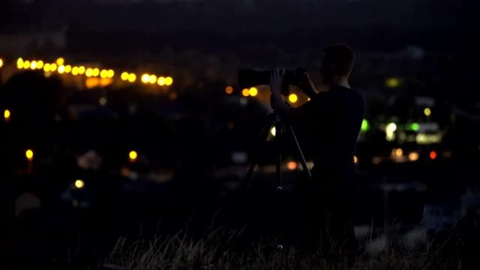 该名男子在夜市灯光的背景下使用相机工作。实时