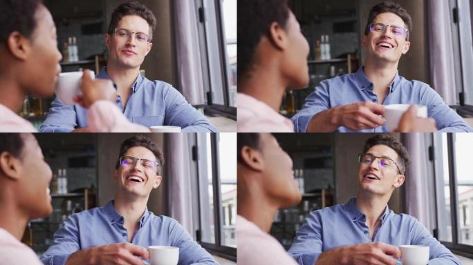 两个快乐的男女朋友坐在咖啡馆喝咖啡，有说有笑