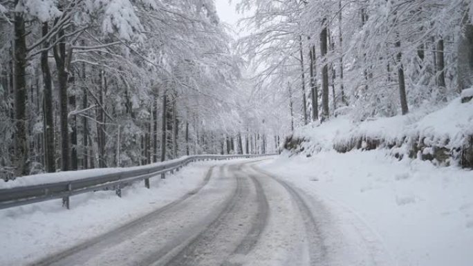 空中: 空旷的雪路蜿蜒穿过斯洛文尼亚乡村的一片安静的森林。