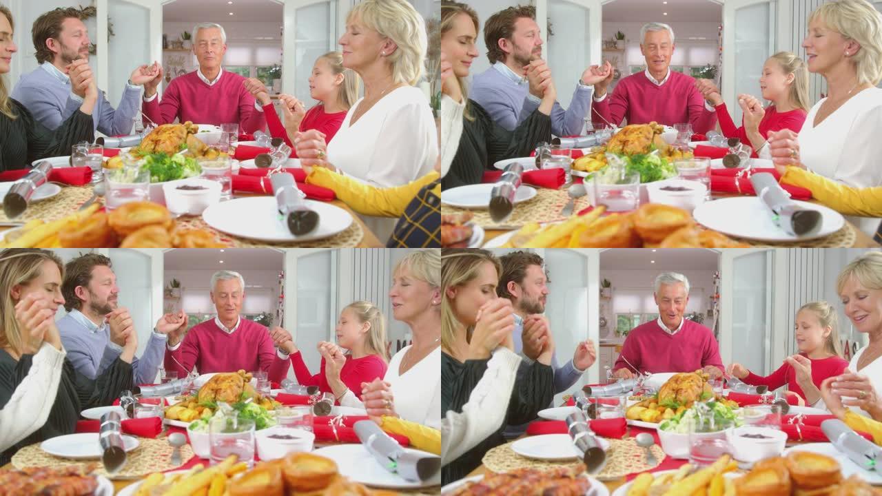 多代家庭在吃圣诞大餐前手牵手在家里的桌子旁说优雅