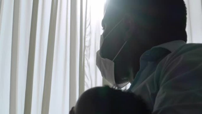 非洲父亲的家庭抱着4个月大的婴儿儿子，并戴着保护性的自信面具，以防止冠状病毒或新型冠状病毒肺炎的流行