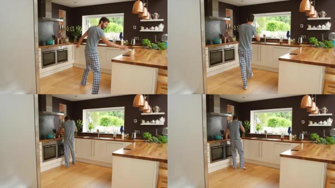 4k视频片段，一个年轻人在煮咖啡时在厨房里跳舞