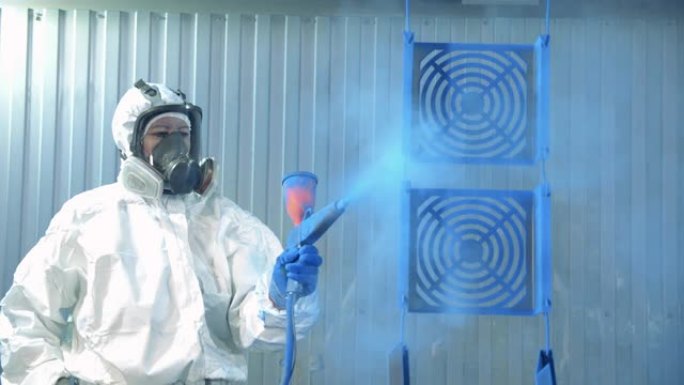 涂装工厂设施的工业涂装工艺。安全磨损的技术人员正在将金属片染成蓝色