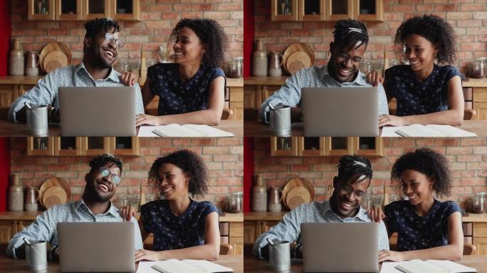 快乐的年轻非洲已婚夫妇在家庭厨房使用笔记本电脑