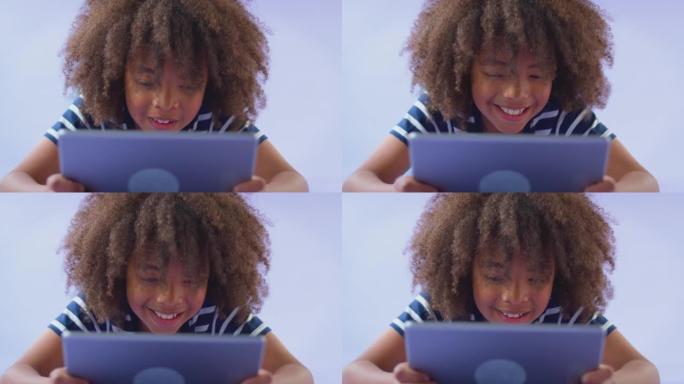 微笑男孩拿着数字平板电脑对着紫色工作室背景的工作室镜头 -- 慢动作镜头
