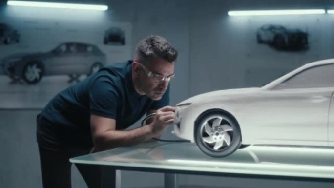 带安全护目镜的汽车工程师使用钢笔工具来完善汽车模型