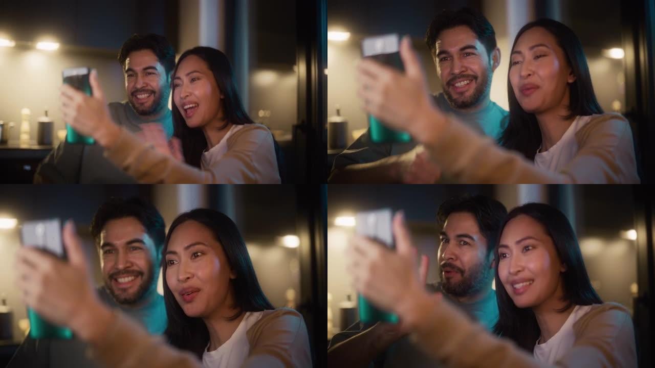 一对幸福的夫妇的肖像，晚上在厨房的智能手机上进行视频通话。他们在聊天。男人和女人使用技术和互联网与家
