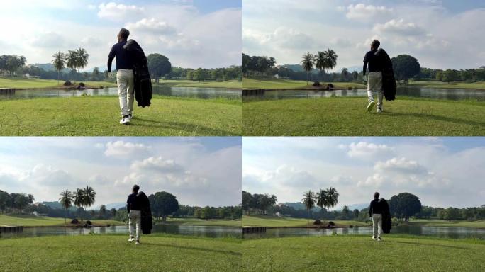 成熟的中国男子高尔夫球手背着高尔夫球袋在高尔夫球场上移开视线