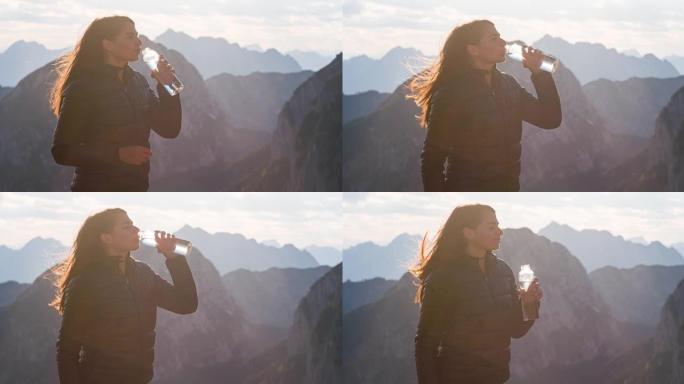 女徒步旅行者在美丽的晴天欣赏山景，喝水