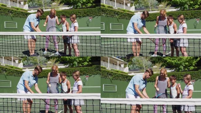 在阳光明媚的日子里，高加索人的父母教他们的孩子在网球场打网球
