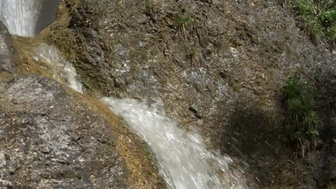 特写: 清晰的水流从闪亮的岩石上冲下的详细视图。