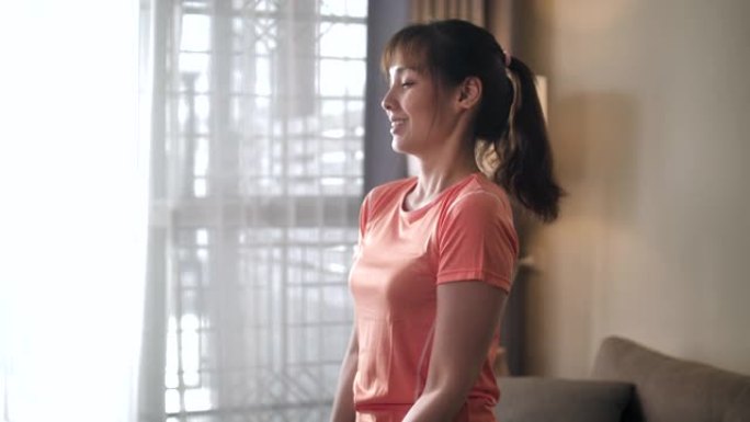 亚洲妇女在家中使用塑料水瓶代替健身房举重运动
