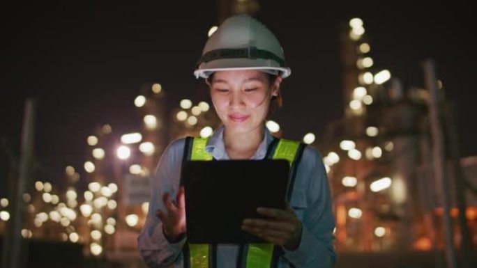 工程师在石油和天然气精炼厂内部使用数字平板电脑在夜间工作