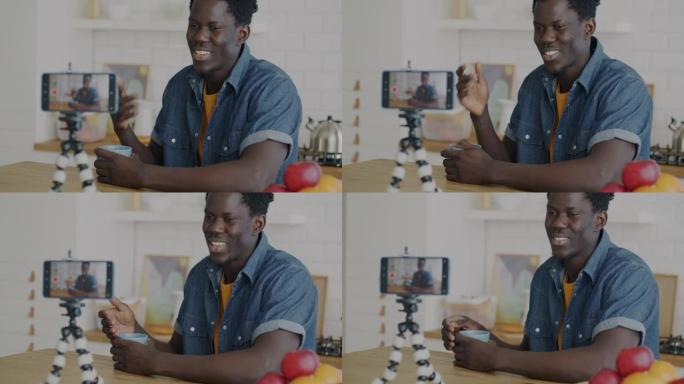 男性视频记录器使用智能手机摄像头为社交媒体录制视频，并在家里的厨房里竖起大拇指