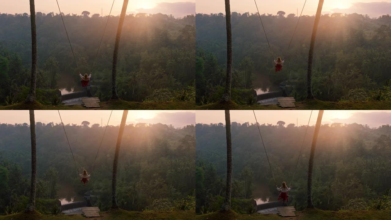 慢动作女人在日出时在热带雨林上摇摆旅行女孩坐在秋千上享受风景享受假期自由享受快乐的假期生活方式