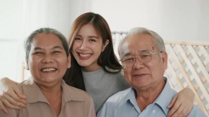 快乐的亚洲民族家庭微笑着拥抱在家里的相机，肖像