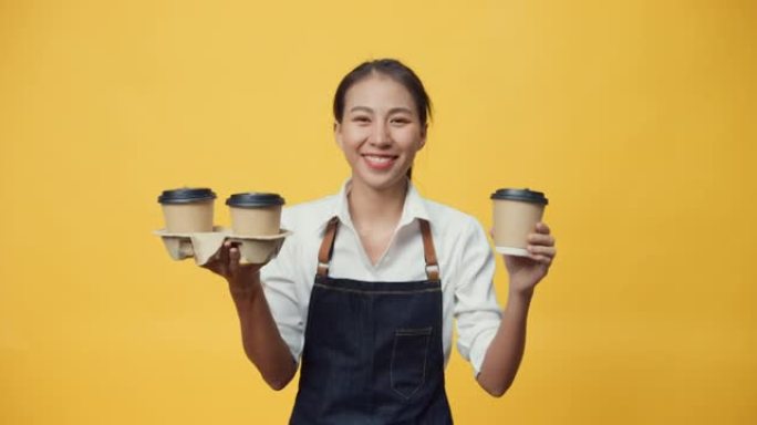 快乐微笑的亚洲女服务员准备接受客户订单，同时看着黄色背景上孤立的相机。
