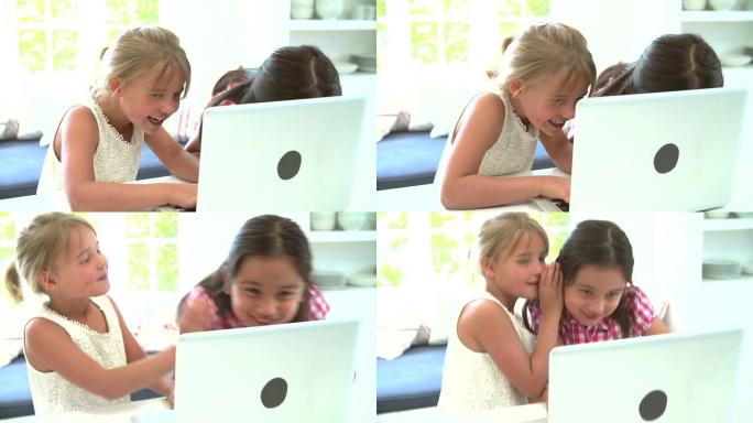 两个年轻女孩在家中使用笔记本电脑并窃窃私语