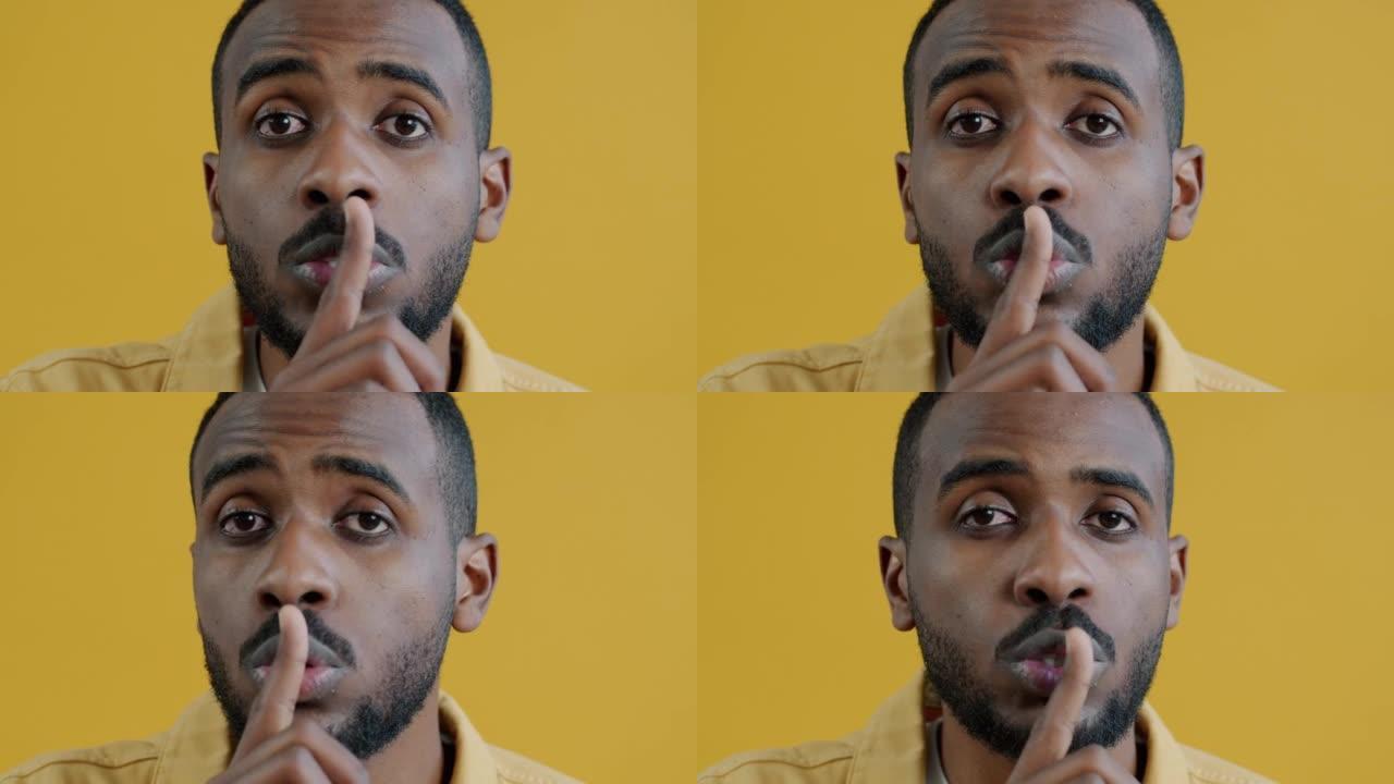 严肃的美国黑人男子的特写肖像用手指安静地触摸嘴唇