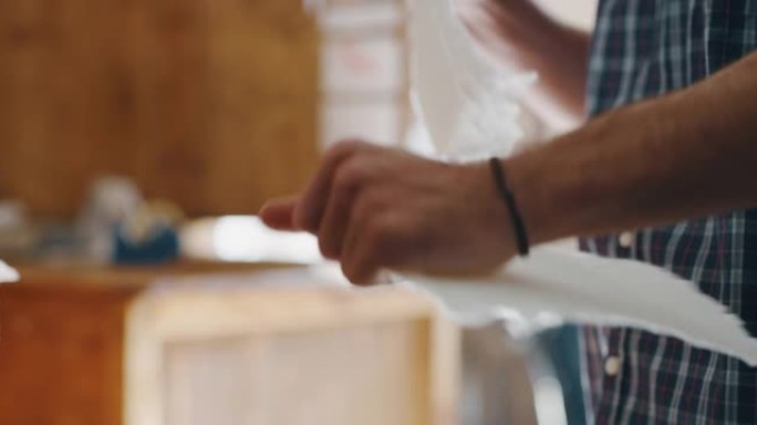 一位工匠造纸大师的特写镜头正在撕下一张手工纸，以控制车间的质量。手工制作的概念，高品质，工匠，意大利