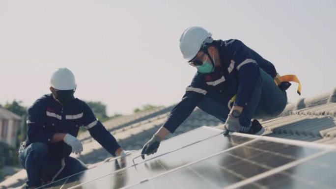 亚洲工人在房屋屋顶上安装太阳能电池板。