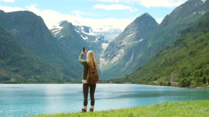4k视频片段，一个无法识别的女人站着并在Sogn og Fjordane的手机上拍照