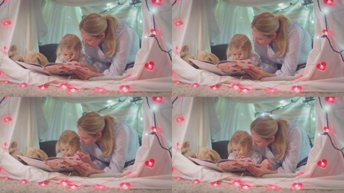 母亲和小女儿在家里孩子卧室的自制营地里读故事