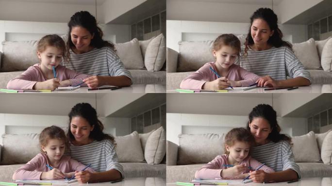 小孩子女儿和有爱心的母亲在纸质相册里画画。